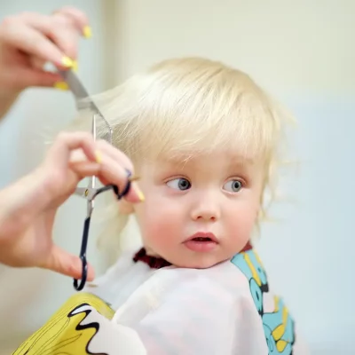 Toddler child getting his first haircut Close up portrait of toddler child getting his first haircut